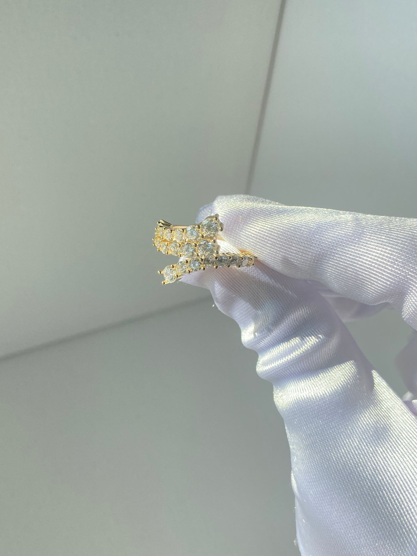 A ring held by a hand, featuring a gold and rhodium plating with cubic zirconia stones set in a classic six-prong setting.