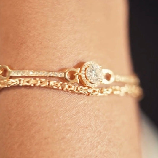 Gold bracelet on a wrist with a dark background
