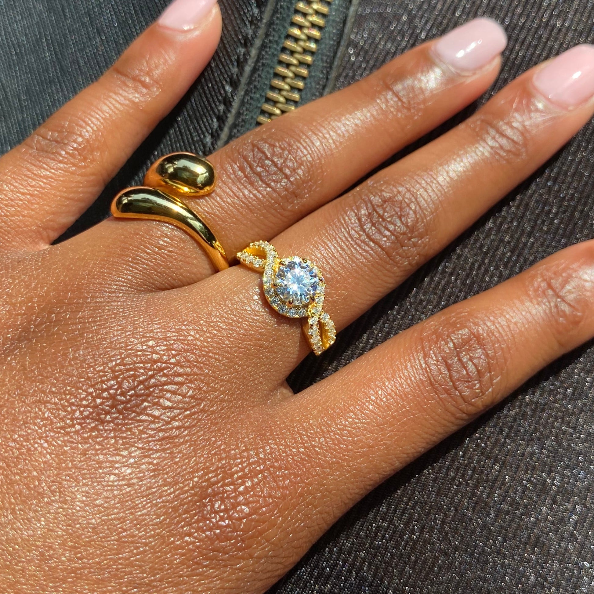 Hand wearing a gold ring with a diamond on a textured surface