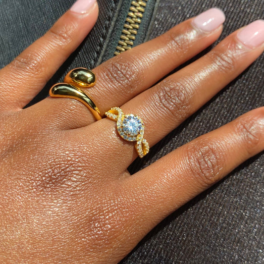 Hand wearing a gold ring with a diamond on a textured surface